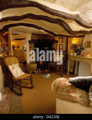 Canne-retour chaise berçante dans petit chalet séjour avec poêle à bois et des poutres au plafond, bas Banque D'Images