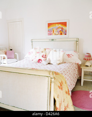 Rose-couette et oreillers peints sur lit laqué blanc en pays blanc chambre Banque D'Images