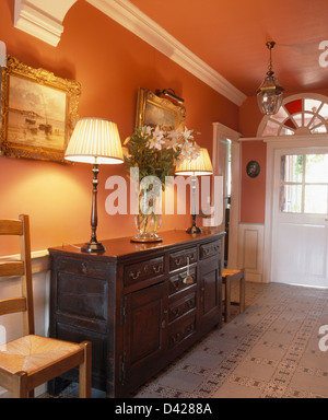 Les lampes allumées sur chêne antique vaisselier gallois en rouge de base French country hall avec sol Banque D'Images