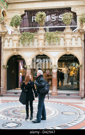 Couple debout à l'extérieur à l'intérieur du magasin Reiss Arcade du comté de Leeds, Angleterre Banque D'Images