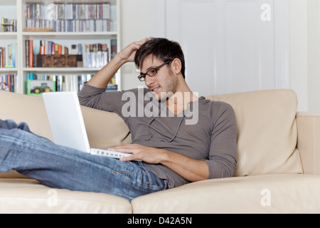 Un homme très confortable surfer sur l'internet à l'aide d'un ordinateur portable. Banque D'Images