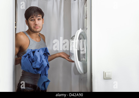 L'homme ayant des problèmes d'utiliser la machine à laver sur Jour de lessive Banque D'Images