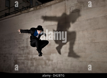 Parkour runner en chapeau melon avec l'ombre, sautant Banque D'Images