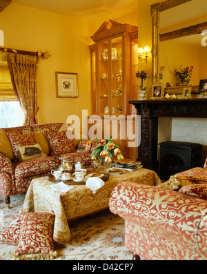 De confortables sofas crème +en terre cuite d'un côté ou d'une table basse recouverte d'un tapis en jaune cottage salon avec lumière mur Banque D'Images