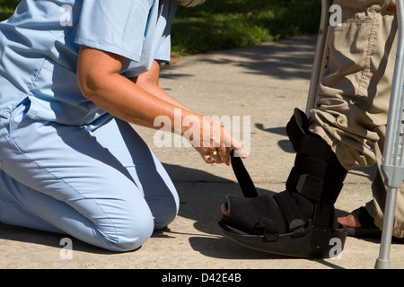 Infirmière d'ajuster la sangle sur le renfort de la cheville du patient. Banque D'Images