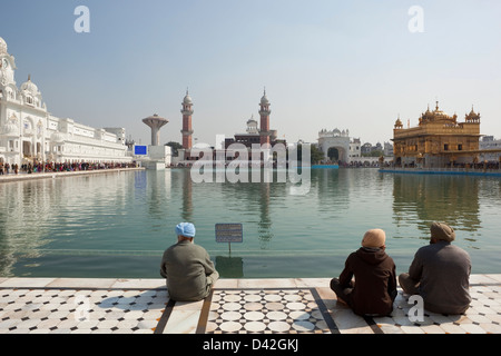 Trois hommes sikhs méditer par la Sainte piscine du complexe Golden Temple à Amritsar, Punjab, India Banque D'Images