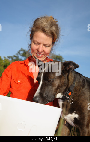 Berlin, Allemagne, une femme avec son ordinateur portable sur la pelouse à côté de son chien Banque D'Images