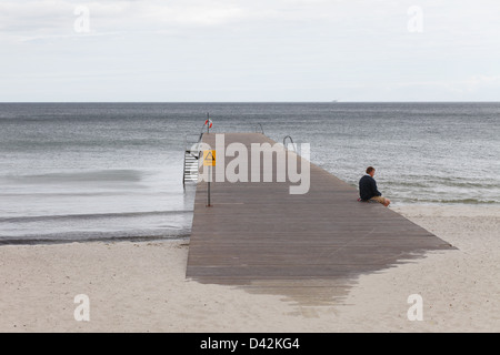 Ystad, en Suède, l'homme assis seul sur une jetée à la côte de la mer Baltique Banque D'Images