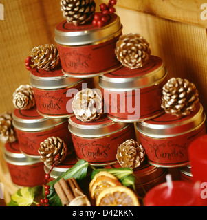 Les pommes de pin peintes d'or disposés sur pyramide de boîtes rouges avec 'Potter & Crouch' bougies Banque D'Images