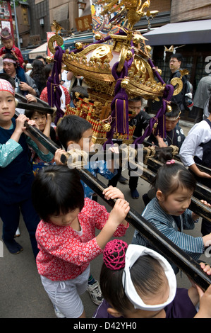 Les garçons et les filles portent une décoration or mikoshi sacré sanctuaire portable à Sanja Matsuri Festival, l'un des trois grands festivals de Tokyo Banque D'Images