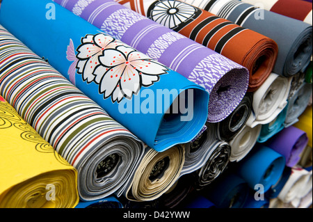 Les boulons de tissu japonais colorés avec une variété de modèles, y compris les fleurs de cerisier est empilé dans une pile dans un magasin à Tokyo. Banque D'Images