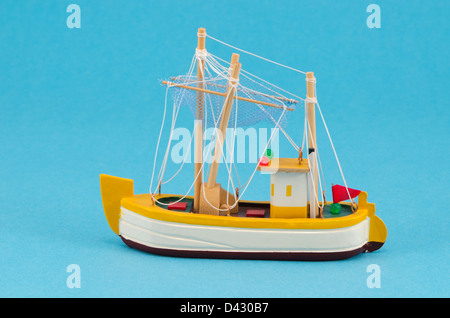 Objet fait main en bois bateau bateau modèle voile avec décor sur fond bleu. Banque D'Images