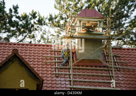 Les hommes travailleurs avec casque couvrant la toiture en tuiles. détail de l'industrie de la construction. Banque D'Images