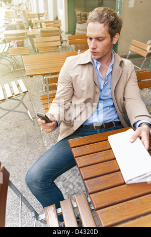 Bel homme dans des vêtements intelligents assis dans un café en plein air Banque D'Images