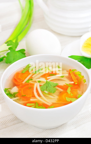 Soupe au poulet avec des légumes dans un bol blanc sur une table Banque D'Images
