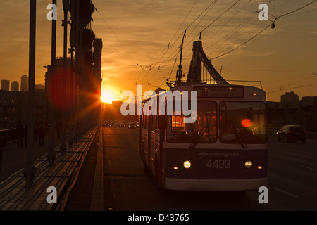 Un trolleybus et des voitures traversant le pont de Crimée à Moscou dans un coucher du soleil la lumière. Banque D'Images