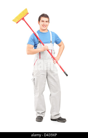 Portrait d'un certain nettoyage dans un uniforme avec un balai contre isolé sur fond blanc Banque D'Images