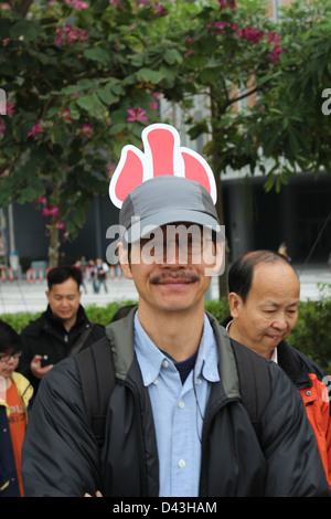 Un homme avec le caractère chinois pour 'petits' sur son chapeau à une manifestation anti-budget à Hong Kong Banque D'Images