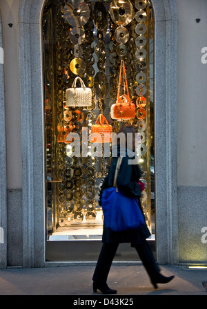 Femme passant d'une fenêtre d'affichage Versace handbags, Via Montenapoleone Milan Lombardie Italie Europe Banque D'Images