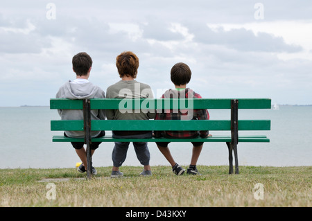 Vue arrière de la mère et du fils assis sur le banc de parc, Ile de Re, France Banque D'Images