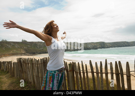 Femme avec bras ouverts à la plage, Camaret-sur-Mer, presqu'île de Crozon, Finistère, Bretagne, France Banque D'Images