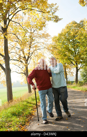 Les hommes aînés marche sur sentier bordé d'arbres en automne, Lampertheim, Hesse, Allemagne Banque D'Images