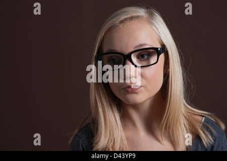 Close-up Portrait of Blond, adolescente, portant des lunettes et à la recherche sur le côté, Studio Shot sur fond noir Banque D'Images