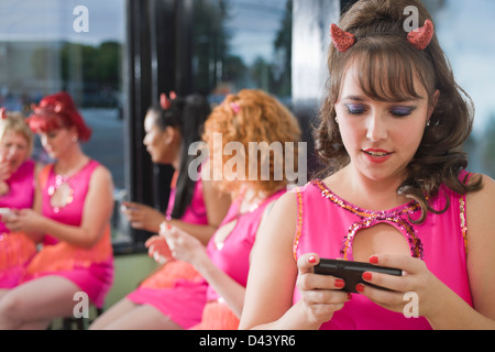 Les femmes portant des cornes de diable et les costumes en utilisant des téléphones cellulaires, Oakland, Alameda County, California, USA Banque D'Images