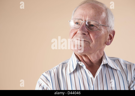 Portrait of Senior Woman wearing Eyeglasses et jusqu'à la dans la distance avec la certitude d'Expression, sur fond beige Banque D'Images