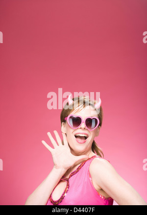 Portrait de femme portant des cornes de diable et lunettes en forme de coeur Banque D'Images