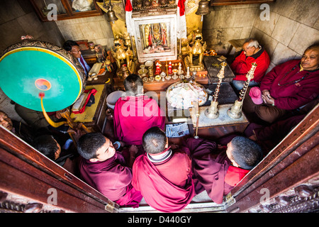 Moines priant dans un hall à praye Stupa Boudhanath, Katmandou, Népal Banque D'Images