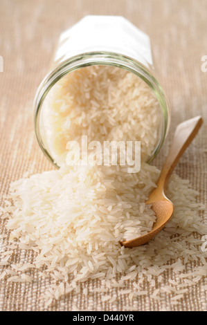 Close-up de riz déversant avec bol en verre de cuillère en bois Banque D'Images