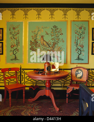 Table et chaises peintes en rouge en face de xviiie siècle, les oiseaux peints en jaune sur le mur de salle à manger avec marbre peint Banque D'Images