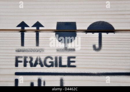 Une boîte en bois imprimée avec l'inscription « fragile » et les symboles de cargaison : deux flèches vers le haut (« this Way UP »), un verre (« fragile - manipulez avec soin ») et un parapluie (« Keep Dry ») est photographiée lors du salon du design DMY à l'aéroport de Berlin Tempelhof en Allemagne, le 5 juin 2011. Fotoarchiv für ZeitgeschichteS.Steinach Banque D'Images