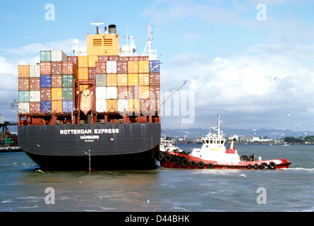 German container ship docks avec l'aide de remorqueur à la borne d'Oakland Banque D'Images