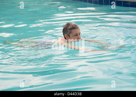 Senior woman natation en piscine turquoise en vacances Banque D'Images