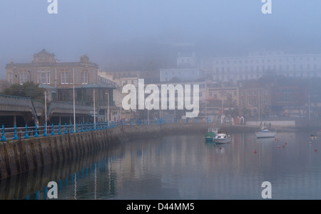 Vue sur le port de Torquay sur un matin, encore, avec sea mist enveloppant les bâtiments. Banque D'Images