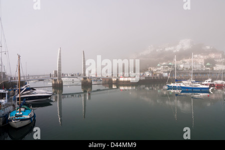 Vue sur le port de Torquay sur un matin, encore, avec sea mist enveloppant les bâtiments. Banque D'Images
