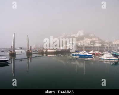 Vue sur le port de Torquay sur un matin, encore, avec sea mist enveloppant les bâtiments. Banque D'Images