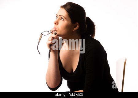 Une jeune femme, les cheveux bruns, assise seule, à la triste bas enfoncé lonely UK holding lunettes lunettes assis Banque D'Images