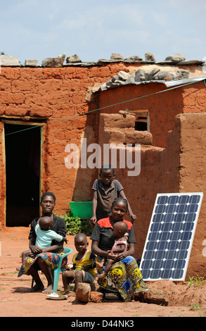 Afrique Angola Kwanza Sul, village Cassombo, Famille avec le système solaire domestique en face de leur hutte en argile Banque D'Images