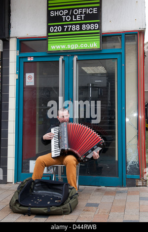 Magasin de vente et bureau de laisser, chômeurs, Busker dans shop porte, jouer Paulo Soprani Accordéon, Blackpool, Lancashire, UK Banque D'Images