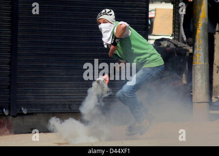 5 mars 2013 - Srinagar, au Cachemire, en Inde - un manifestant du Cachemire lance un nouveau shell gaz lacrymogènes vers des policiers indiens lors d'un affrontement entre les manifestants et la police indienne à Srinagar, la capitale d'été du Cachemire indien. La vie normale a été frappé pour la deuxième journée consécutive, aujourd'hui, grâce à une marche organisée par un groupe de séparatistes à la résidence d'un étudiant du Cachemire, qui a été retrouvé pendu dans sa chambre à l'auberge à Hyderabad. Les autorités ont déployé du personnel de police et paramilitaires en grand nombre dans le sud du Cachemire Pulwama ville, la région de Mudasir Kamran, (25) qui a été retrouvé pendu dans la Banque D'Images