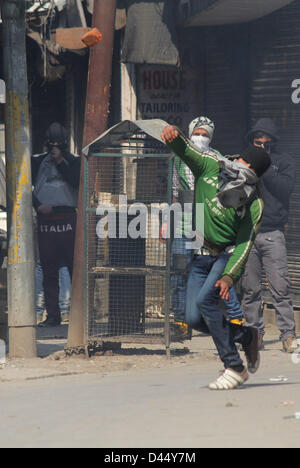 5 mars 2013 - Srinagar, au Cachemire, en Inde - un manifestant lance des pierres sur du Cachemire policiers indiens lors d'un affrontement entre les manifestants et la police indienne à Srinagar, la capitale d'été du Cachemire indien. La vie normale a été frappé pour la deuxième journée consécutive, aujourd'hui, grâce à une marche organisée par un groupe de séparatistes à la résidence d'un étudiant du Cachemire, qui a été retrouvé pendu dans sa chambre à l'auberge à Hyderabad. Les autorités ont déployé du personnel de police et paramilitaires en grand nombre dans le sud du Cachemire Pulwama ville, la région de Mudasir Kamran, (25) qui a été retrouvé pendu au plafond de son hôte Banque D'Images