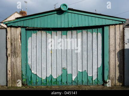 Un affaissement et porte de garage délabré avec de la peinture verte de déroulage Banque D'Images