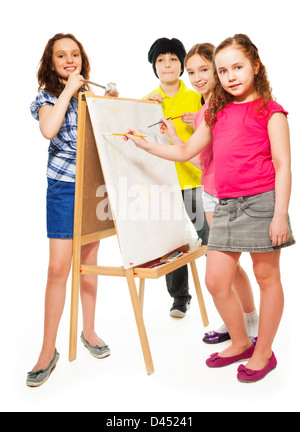 Groupe de quatre enfants, garçons et filles avec peinture pinceaux sur la toile blanche Banque D'Images