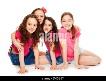 Quatre mignons petits 10 ans Filles en rose assis, souriant et l'air heureux, isolated on white Banque D'Images