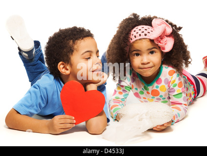 Garçon noir portant sur l'étage avec petite fille aux cheveux crépus holding red heart en papier Banque D'Images