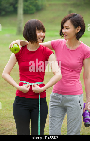 Femme chinoise mesurant la forme de belle taille avec sourire pour un mode de vie sain concept avec la nature fond vert Banque D'Images