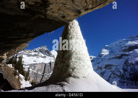 Icecone sur falaise en surplomb au-dessus du lac Oeschinen congelé, Alpes Bernoises, Suisse Banque D'Images